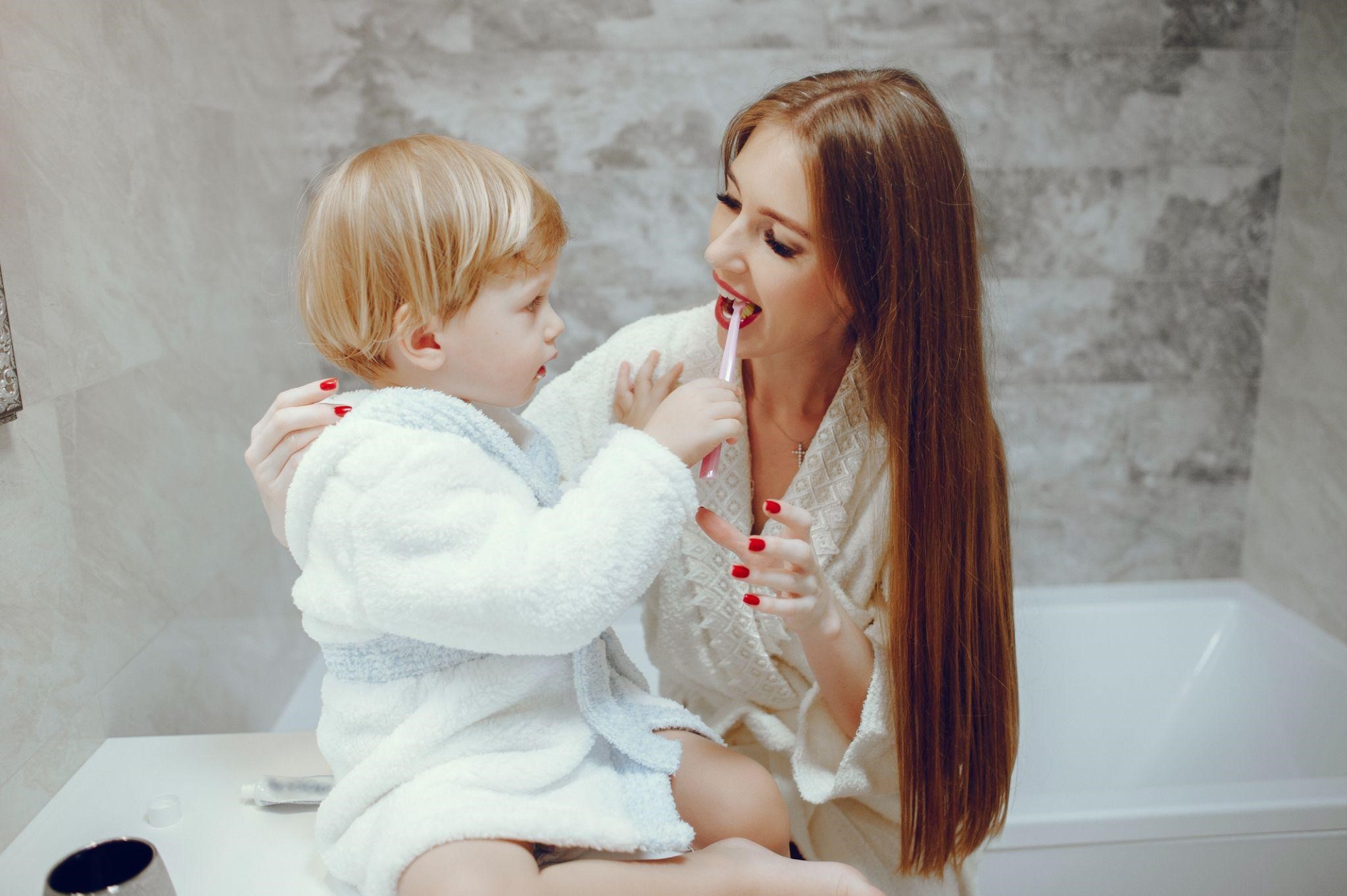 A child brushing his mom's teeth